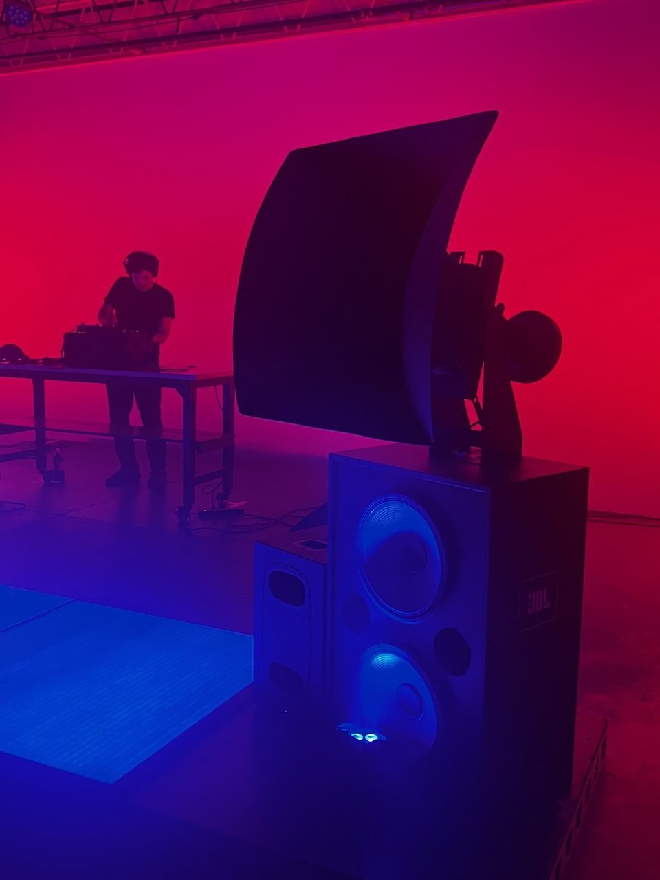 The empty dadaLab room washed in red and blue light, a large speaker stack in the foreground